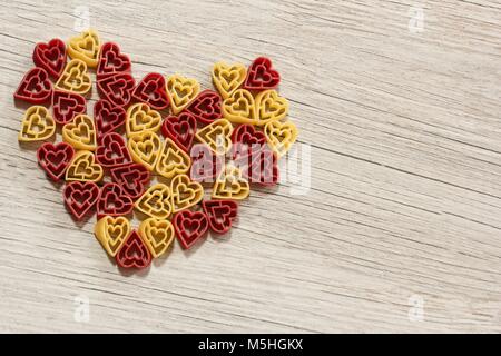 Mutil pasta colorata formando forma di cuore / San Valentino di sfondo alimentare Foto Stock