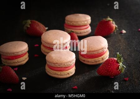 In casa rosa Macarons francese nero su sfondo di legno Foto Stock