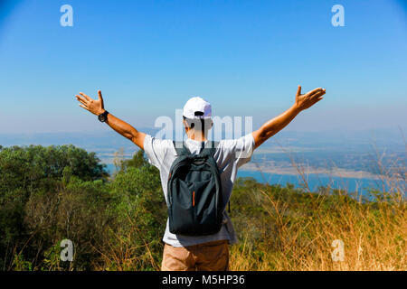 Avventuroso uomo è in piedi sulla cima della montagna e godendo della splendida vista Foto Stock