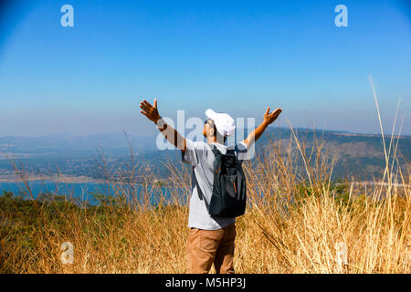 Avventuroso uomo è in piedi sulla cima della montagna e godendo della splendida vista Foto Stock