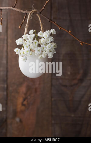 Mazzetto di di bianco del bambino fiori respiro (gypsophila) nel guscio delle uova sul brown tavolato in legno. Profondità di campo, concentrarsi sul vicino a fiori. La pasqua con Foto Stock