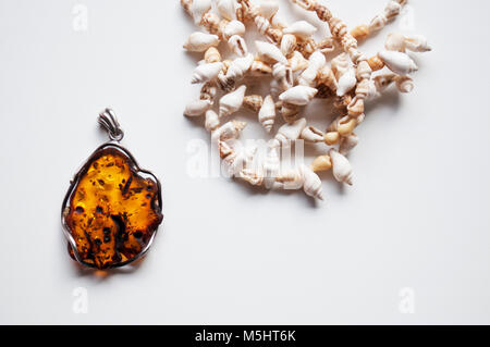 Ambra pendente con collana di conchiglie su sfondo bianco Foto Stock