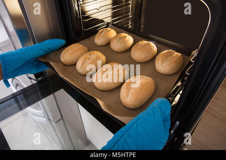 Vista in alzata di mano di una persona tenendo il vassoio di pasta di pane cotto al forno Foto Stock