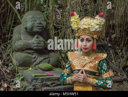 Ballerino di danza Balinese con statua del Buddha, sacro Santuario della Foresta delle Scimmie, Ubud, Bali Foto Stock