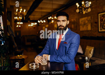 Ritratto di giovane elegante uomo in un bar con lo sbarramento rotante Foto Stock