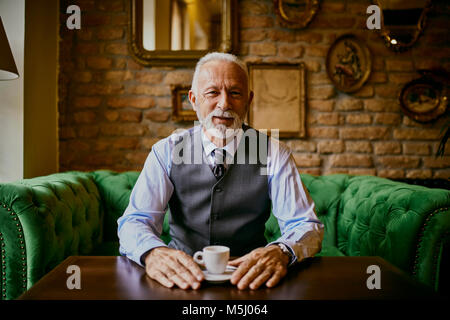 Ritratto di senior elegante uomo seduto sul lettino in un cafe Foto Stock