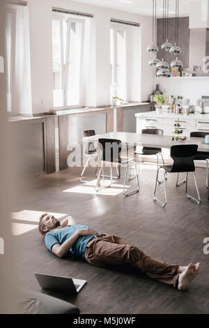 Uomo disteso sul pavimento in un soppalco avente un periodo di riposo Foto Stock