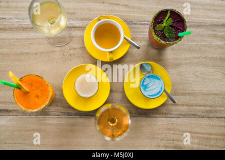 Tavolo in legno con diversi tipi di bevande come puffo latte, smoothie, vino e tè Foto Stock