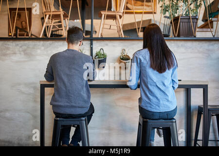 Vista posteriore della giovane donna e uomo seduto in un bar Foto Stock