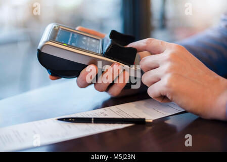 Uomo che utilizza un lettore di carte di credito, close-up Foto Stock