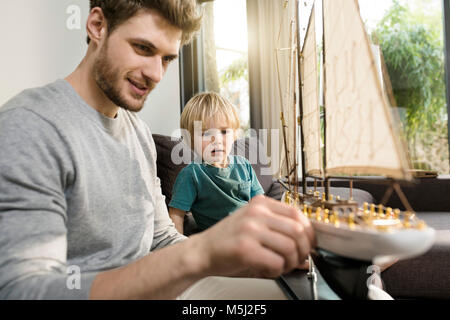 Padre e figlio guardando toy Modello di nave sul lettino a casa Foto Stock