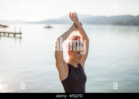 Donna in sportswear stiramento ad un lago Foto Stock