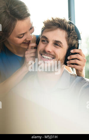 Donna sorridente mettendo sulle cuffie sul ragazzo Foto Stock