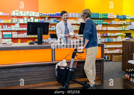 Il farmacista medicina dando al cliente con scuotipaglia con ruote in farmacia Foto Stock