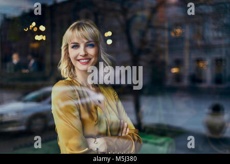 Ritratto di sorridente donna elegante dietro il vetro di finestra Foto Stock