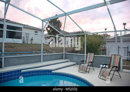 Giardino sul retro di una casa con piscina e sedie con un rilassante tramonto Foto Stock