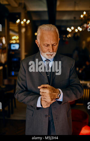 Elegante uomo senior regolando il suo polsi Foto Stock