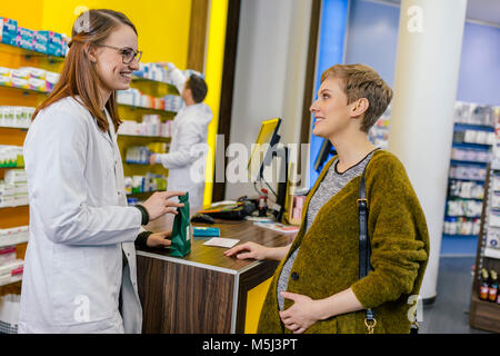 Il farmacista di consigliare la donna incinta in farmacia Foto Stock