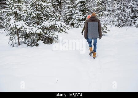 Giovane a piedi nella foresta di inverno Foto Stock