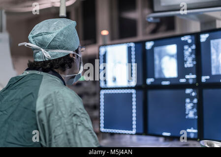 Neuroradiologist in scrubs guardando il monitor Foto Stock