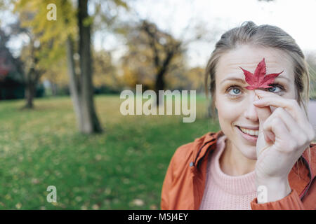 Ritratto di giovane donna con foglie di autunno in un parco Foto Stock