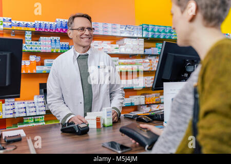 Il farmacista medicina spiegando al cliente in farmacia Foto Stock