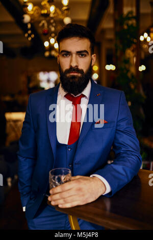 Ritratto di giovane elegante uomo in un bar, in un bicchiere di contenimento Foto Stock