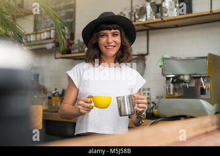 Ritratto di donna con cappello nero dietro il bar di preparare un caffè Foto Stock