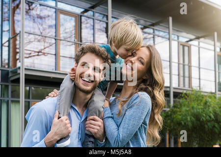 Genitori felici con il figlio davanti alla loro casa Foto Stock