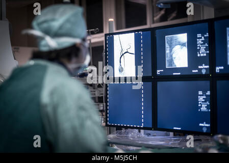 Neuroradiologist in scrubs guardando il monitor Foto Stock