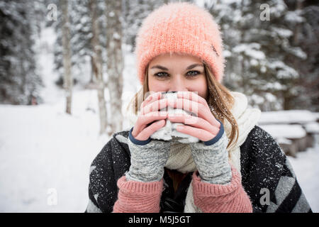 Ritratto di giovane donna di bere una bevanda calda all'aperto in inverno Foto Stock