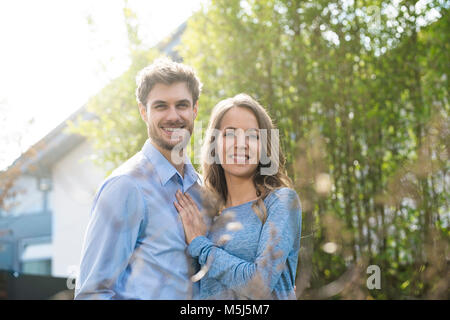 Ritratto di Coppia sorridente nel giardino davanti di piante di bambù Foto Stock