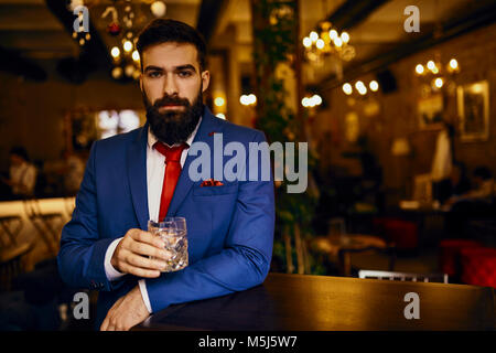 Ritratto di giovane elegante uomo in un bar, in un bicchiere di contenimento Foto Stock