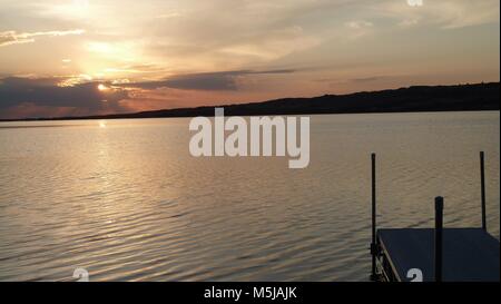 Un incredibile sunrise al mattino presto si affaccia sul lago con una dock sul margine Foto Stock