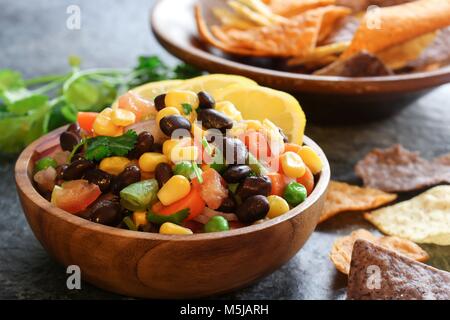 In casa del fagiolo nero salsa di mais con Patatine serviti in una ciotola di legno, fuoco selettivo Foto Stock