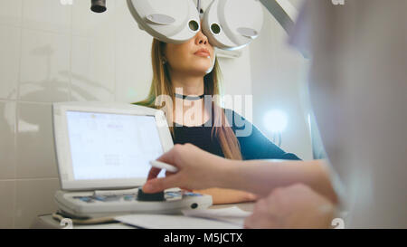 Donna facendo prova di occhio con all'ottico optometrista nel centro medico Foto Stock