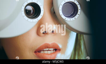 Giovane donna con labbra rosse che controlli gli occhi sulle attrezzature moderne nel centro medico Foto Stock