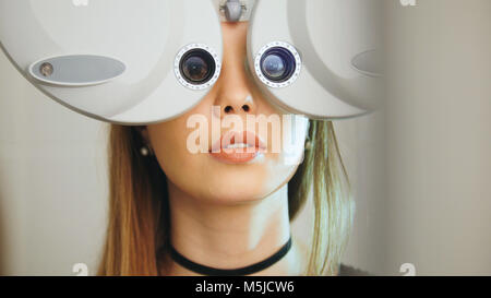 Attraente ragazza con labbra rosse che controlli gli occhi sulle attrezzature moderne nel centro medico, teleobiettivo Foto Stock