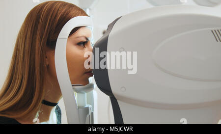 Oftalmologia Clinica concetto - giovane femmina attraente facendo visione di controllo dalla moderna tecnologia elettronica Foto Stock