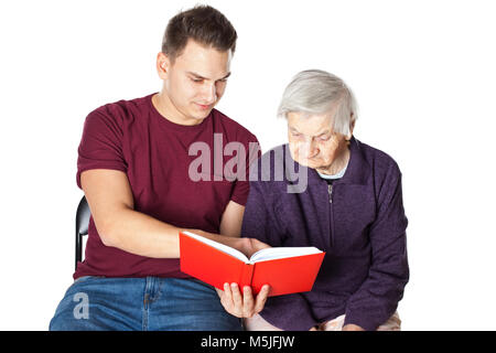 Bel giovane la lettura di un romanzo con anziani disabili nonna su sfondo isolato Foto Stock