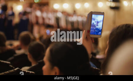 Il pubblico in sala da concerto durante l esecuzione di pianoforte ragazza- persone prestazioni di scatto sullo smartphone, musica opera Foto Stock