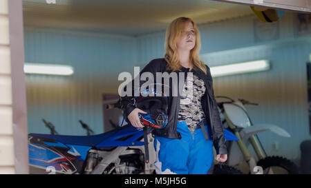 Donna MXgirl con il motocross casco in garage Foto Stock