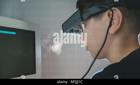 Oftalmologia - bambino ragazzo controlla gli occhi con occhiali stereo e monitor Foto Stock