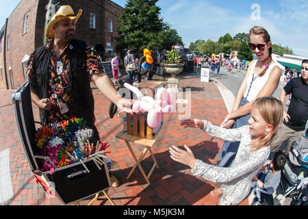 Un palloncino animale mani fornitore una bambina di un palloncino Cat In The scarecrow Harvest fall festival di Alpharetta, GA, il 30 settembre 2017. Foto Stock