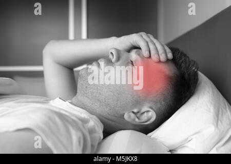 Uomo disteso nel letto di casa che soffrono di mal di testa o i postumi della sbornia Foto Stock
