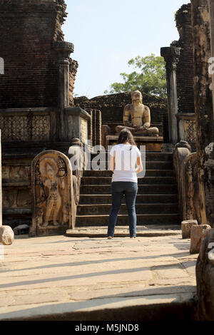 Polonnaruwa quadrangolo Nord provincia centrale dello Sri Lanka il Vatadage Tourist in piedi nella parte anteriore del Buddha seduto in posizione Virasana con mani in Foto Stock