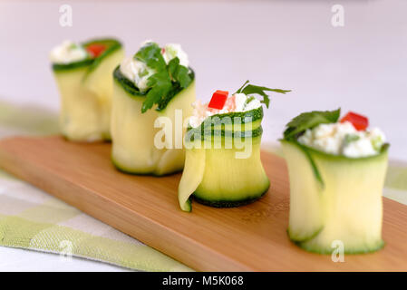 Rotoli di zucchine ripiene di formaggio e erba cipollina e la paprica rossa. Foto Stock