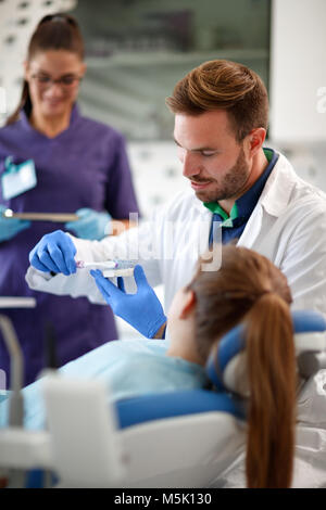 Dentista mostra sulla mandibola con denti modello al giovane ragazza il modo corretto di lavarsi i denti Foto Stock