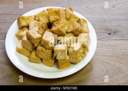 Dolce fritto i cubetti di tofu in piastra bianca su sfondo di legno Foto Stock