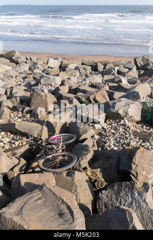 Abbandonato bicicletta su rocce sulla riva del mare Seaton Carew, Hartlepool, Cleveland, England, Regno Unito Foto Stock